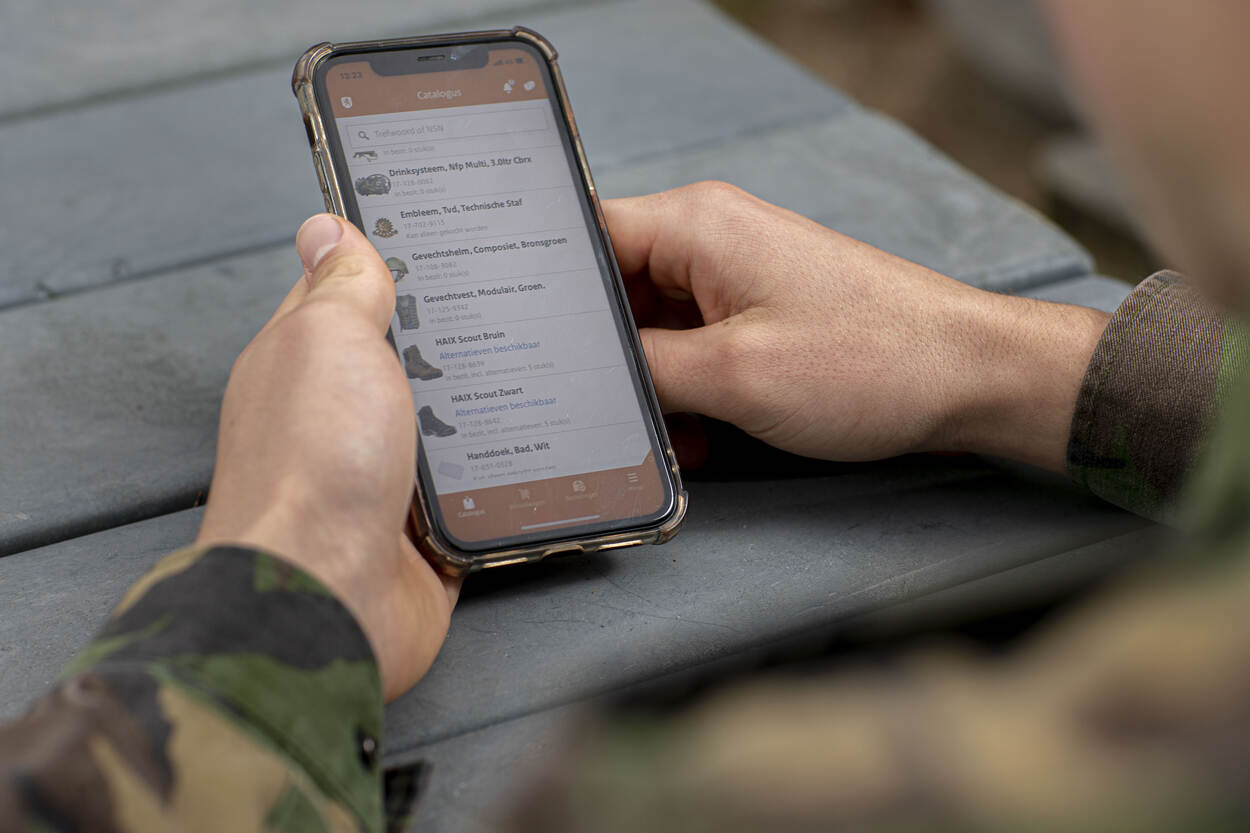 Militair houdt een smartphone met de nieuwe KPU-app vast.