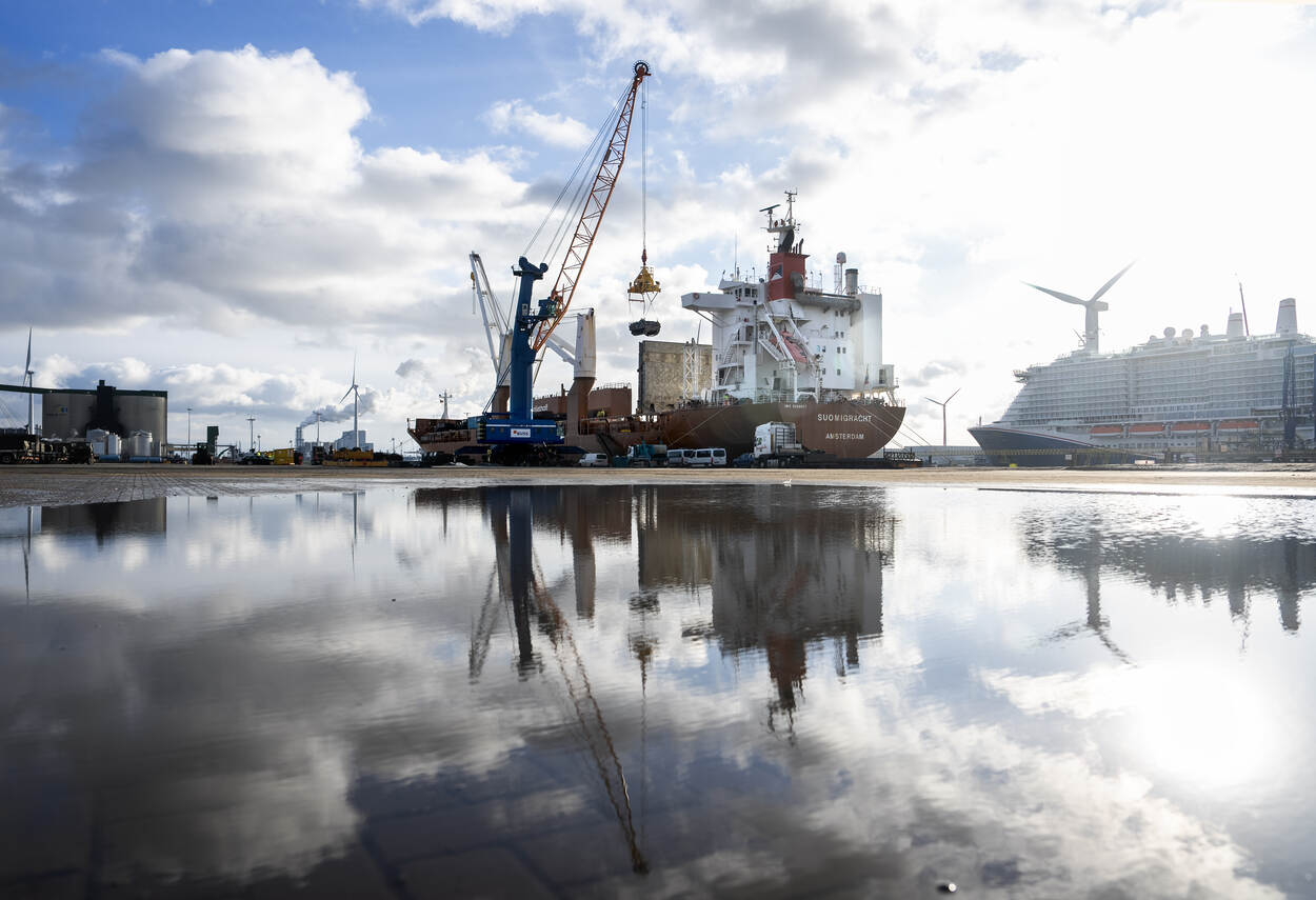 Vrachtschip aan de kade van de Eemshaven met een reflectie in een grote waterplas.