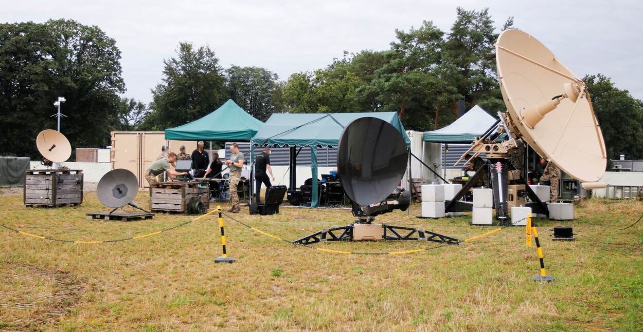 Meerdere satcom-schotels en apparatuur op een testlocatie.