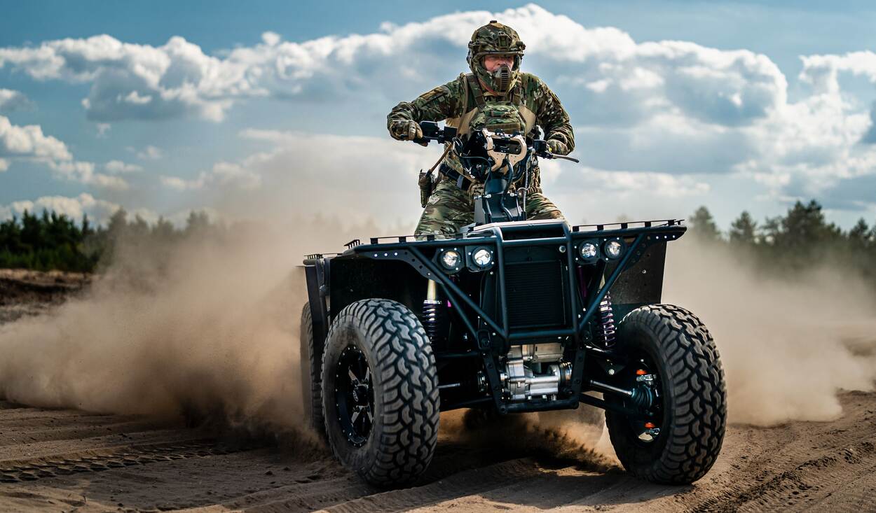 Hybride quad in de verte met stof op een zandweg.