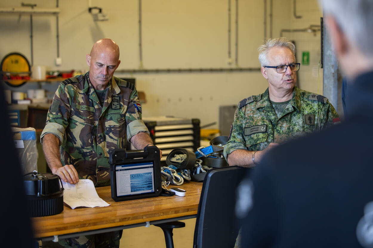 Overste Wim en sergeant-majoor Dave in uniform bij tafel met tablet.