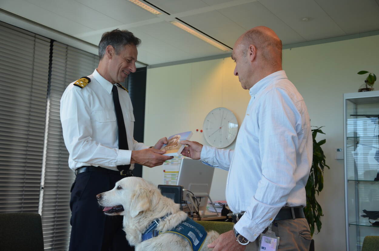 Auteur Royan van Velse overhandigt zijn boek aan de commandant van COMMIT