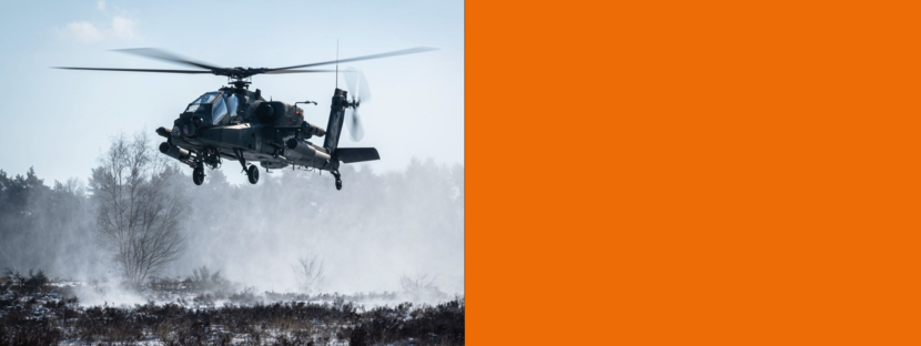 Een Apache-gevechtshelikopter vliegt laag boven de grond.