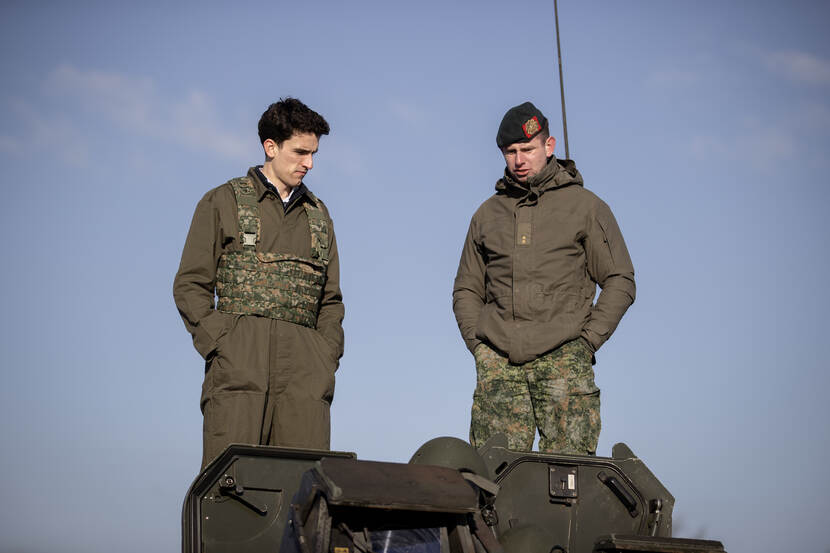 Op de foto een fractiemedewerker en een militair op het dak van en CV90 gevechtsvoertuig.