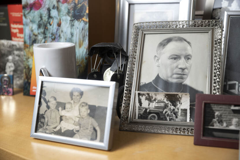 Een houten dressoir met daarop verschillende oude foto’s van Bert Carper en z’n familie in sepia en zwart wit in houten lijsten.