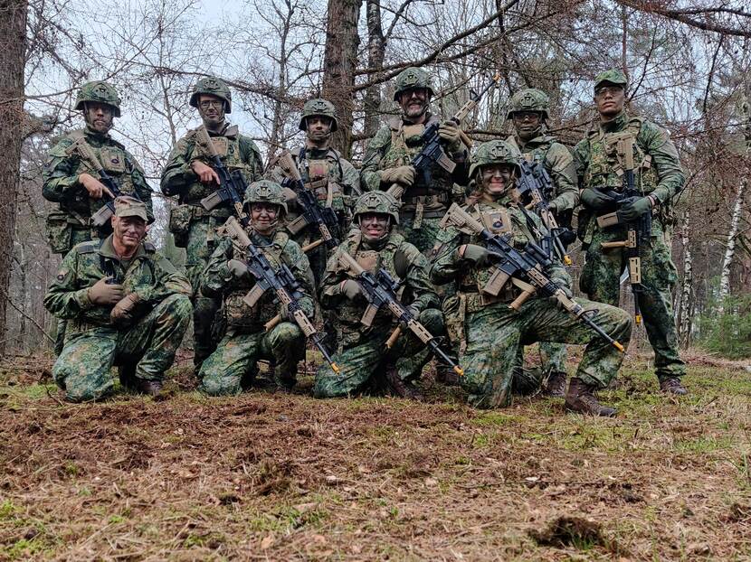 Een groepsfoto van gecamoufleerde reservisten in het bos.