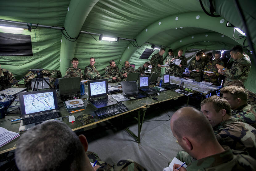 Een commandocentrum in een tent met een lange tafels vol computers en militairen die daarmee werken.