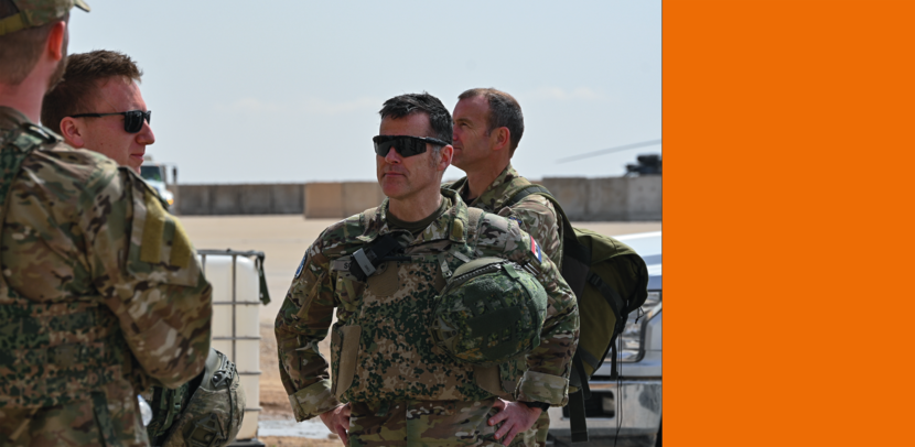 Luitenant-generaal met GVT aan en helm onder z’n arm op een basis in Irak praat met collega’s.