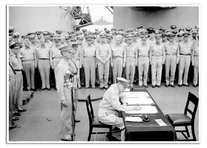 Aan boord van een schip staat de bemanning in rijen opgesteld rond een tafel, terwijl generaal MacArthur de overgave van Japan ondertekent.
