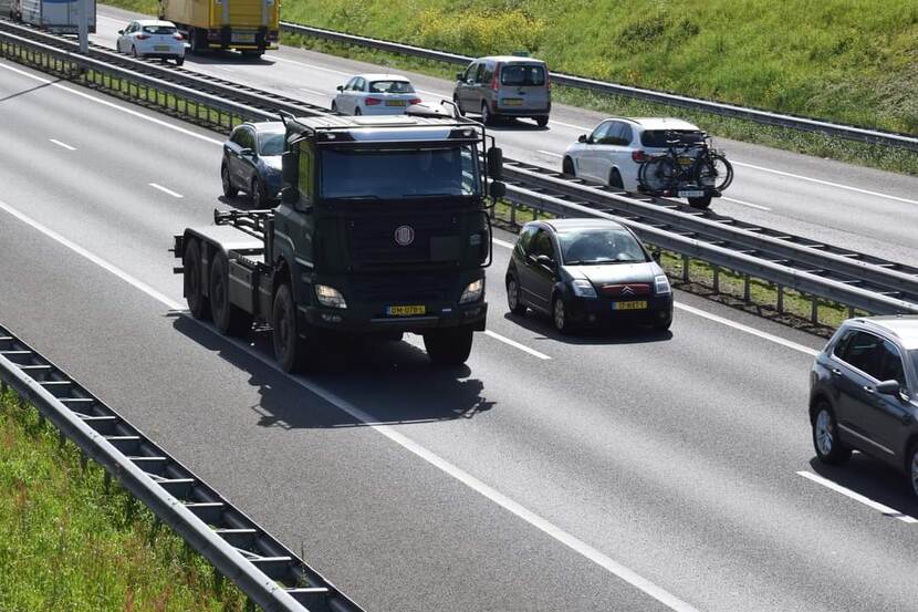 Defensievoertuig rijdt over de snelweg, net voor een viaduct.