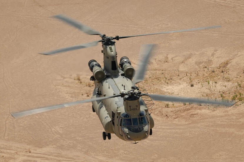 Een Chinook-transporthelikopter vliegt over de zandvlakte ergens boven Irak.