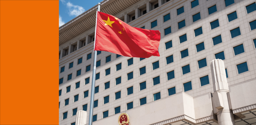 Een Chinese vlag wappert voor een wit gebouw wat het ministerie van Defensie in China is.