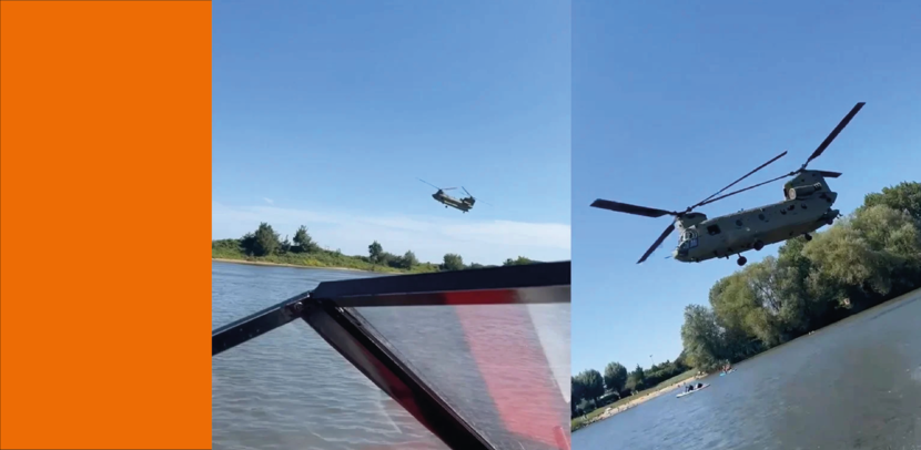 Laagvliegende Chinook hangt laag boven de Maas, naast een speedboot die daar op dat moment rondvaart.