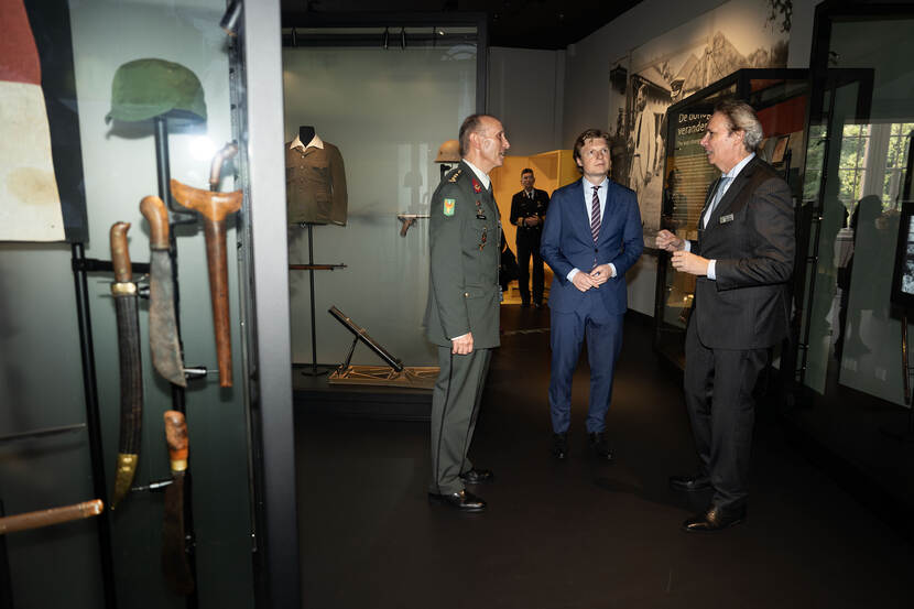 Rechts kolonel Van Kuijck en links hoofd museum Pauljac Verhoeven geven in het museum uitleg bij de vitrines aan minister Brekelmans.