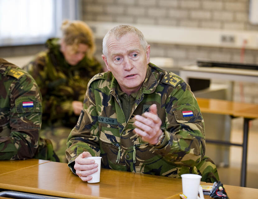 Archieffoto van Van Uhm in groen GVT in een leslokaal in gesprek met studenten.