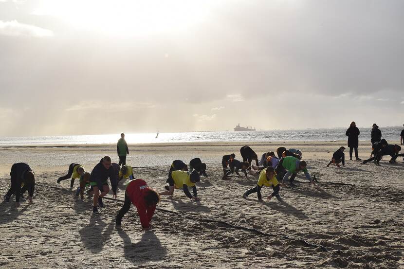 Kinderen spelen aan strand en zee met op achtergrond een boot