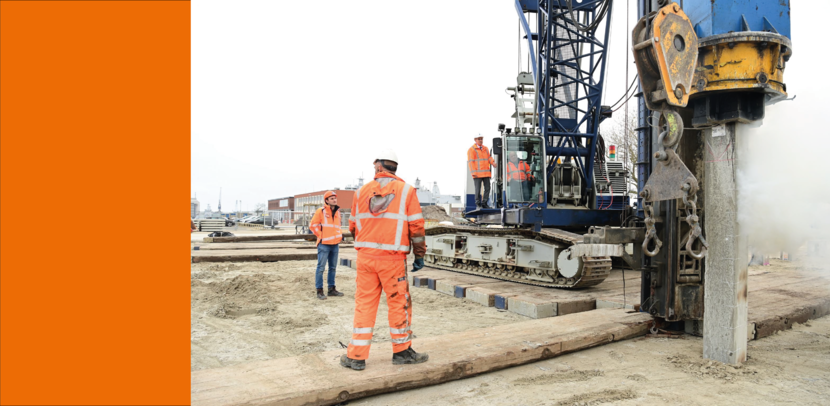 Werkers kijken terwijl een heimachine het werk doet.