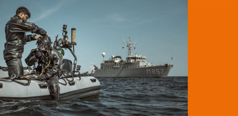 Marineduikers op een rubberboot, op de achtergrond mijnenjager Makkum.