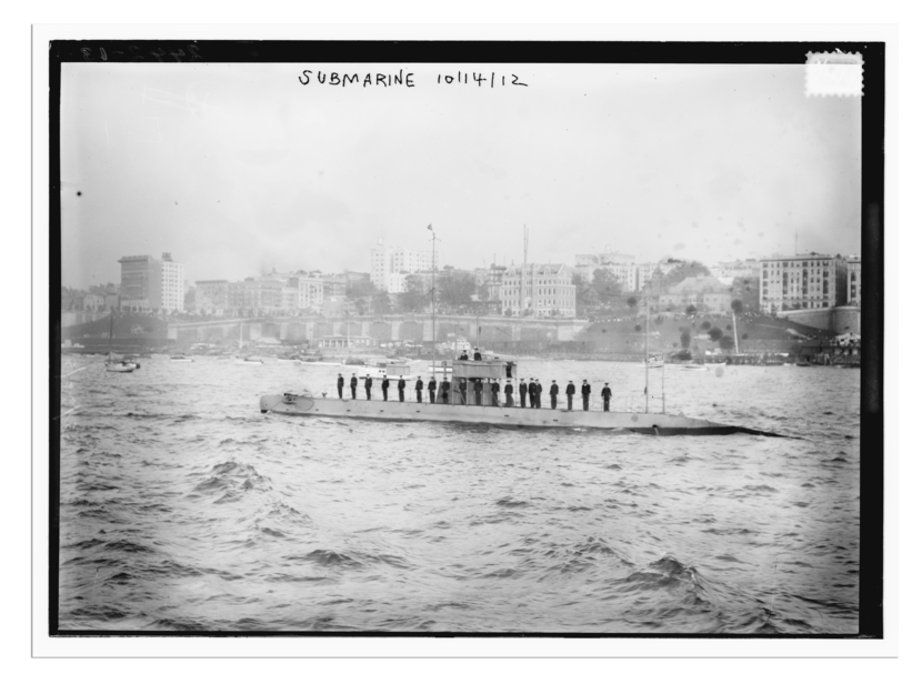 De E1 vaart weg, met de haven op de achtergrond. De bemanning staat buiten.