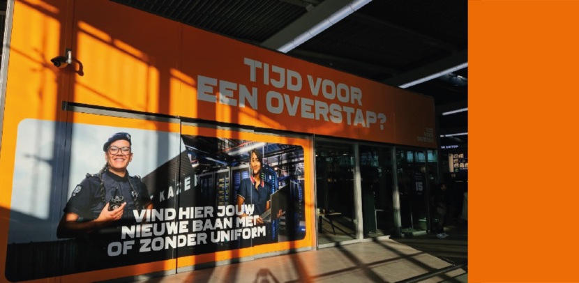 Beeld van de popup-store. Op een oranje banier prijkt de tekst: ‘Tijd voor een overstap? Vind hier jouw nieuwe baan met of zonder uniform.’
