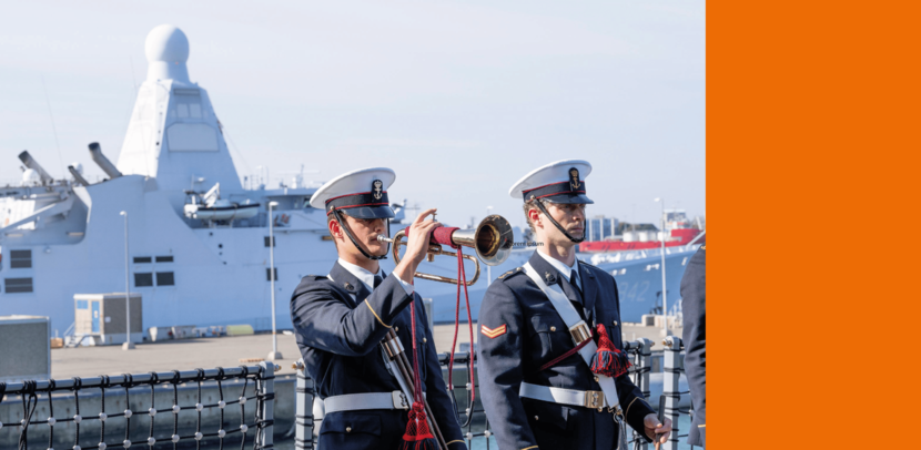 2 muzikanten van de marine trompetteren voor een marineschip.