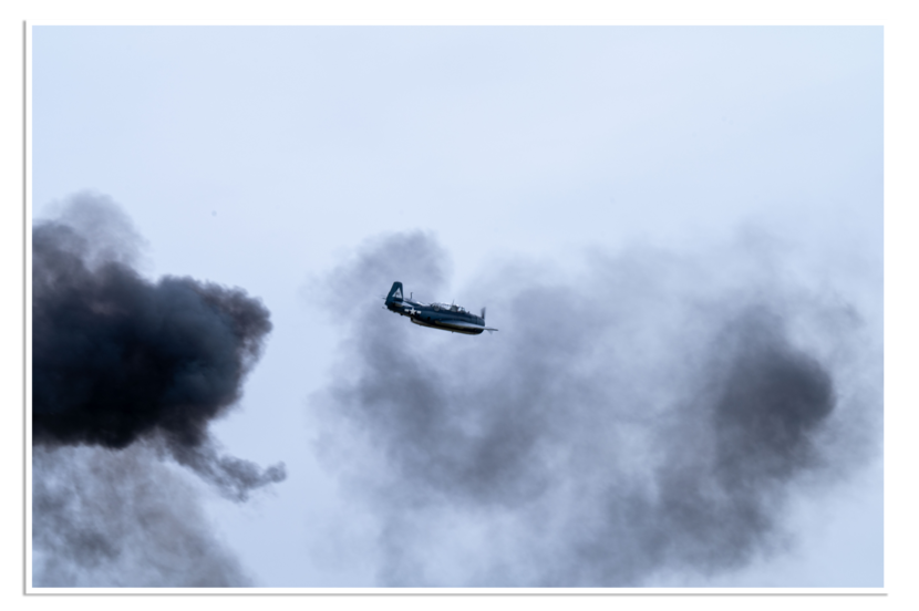 Een oud propellervliegtuig vliegt door de lucht en rookwolken.