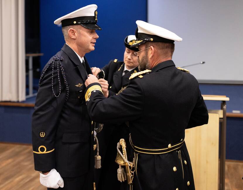 Admiraal Tas en zijn adjudant halen het nestel van het uniform van adjudant Hijman af.