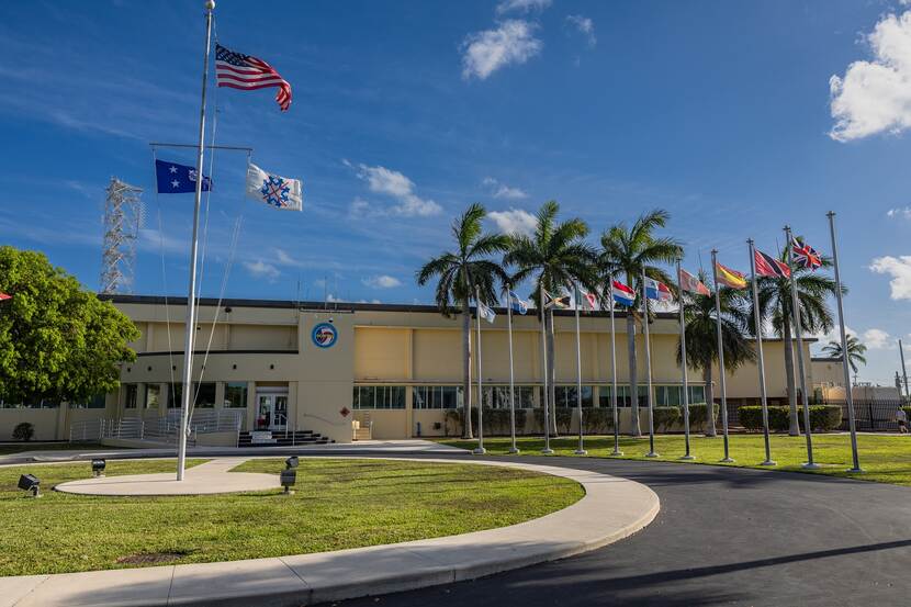 Het geelgekleurde hoofdkwartier van JIATF-S in Key West. Voor het gebouw wapperen vlaggen van verschillende landen, waaronder die van Nederland.