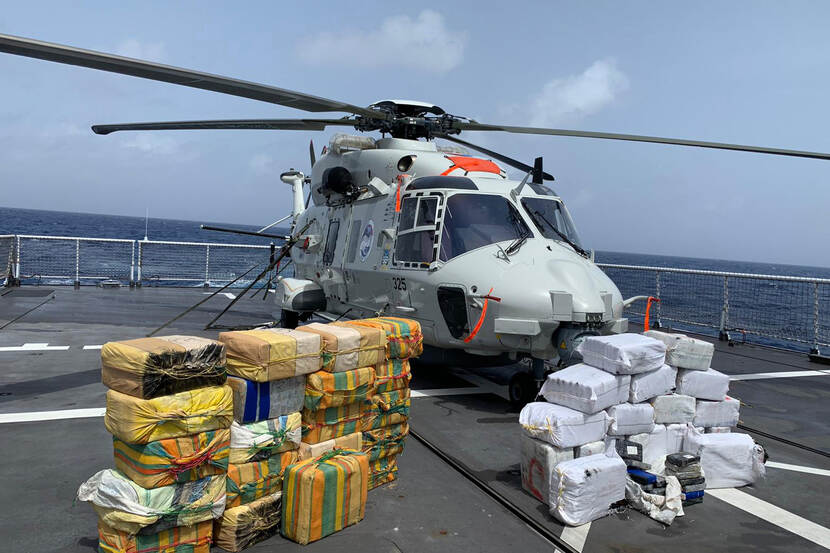 Een stapel met drugspakketten op het dek van een marineschip, met daarachter een helikopter.