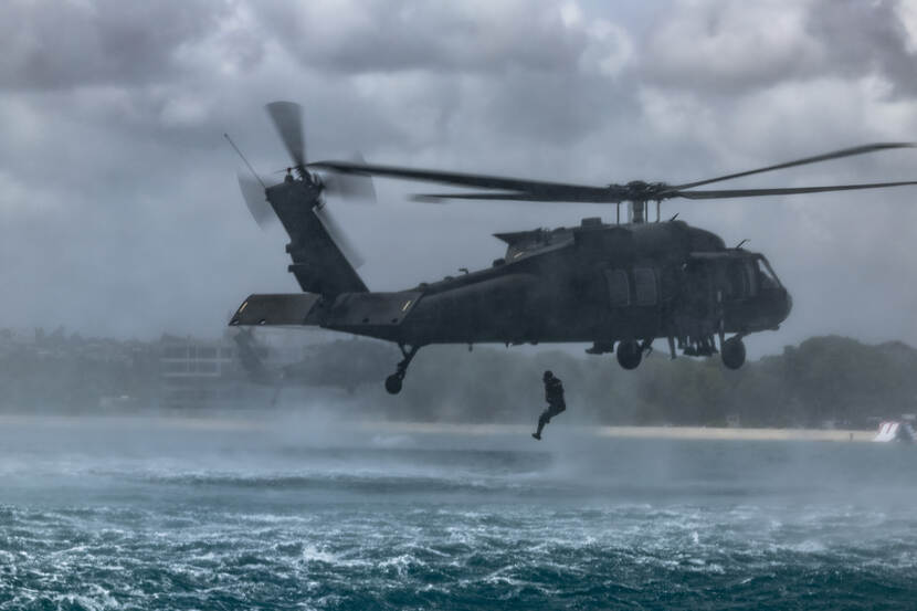 Een marinier wordt boven zee uit een helikopter gedropt.