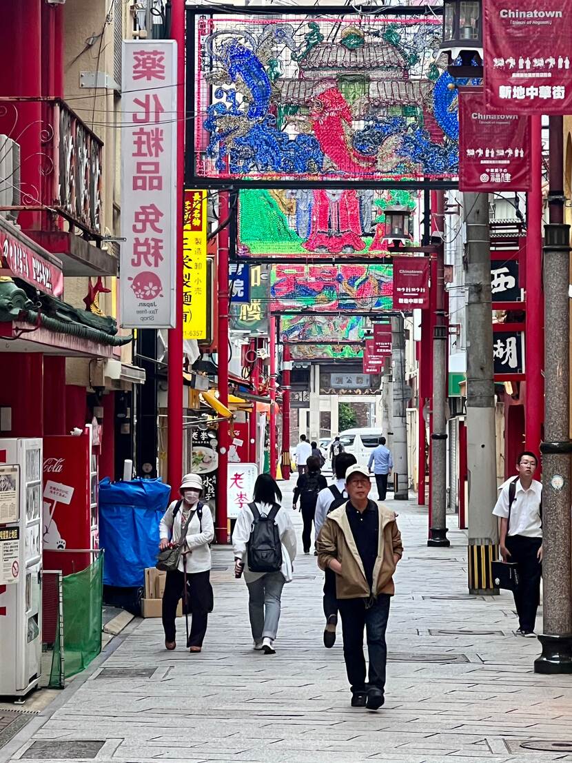 Een man loopt door een straat die versierd is met allerlei gekleurde linten, met daarop Japanse teksten.