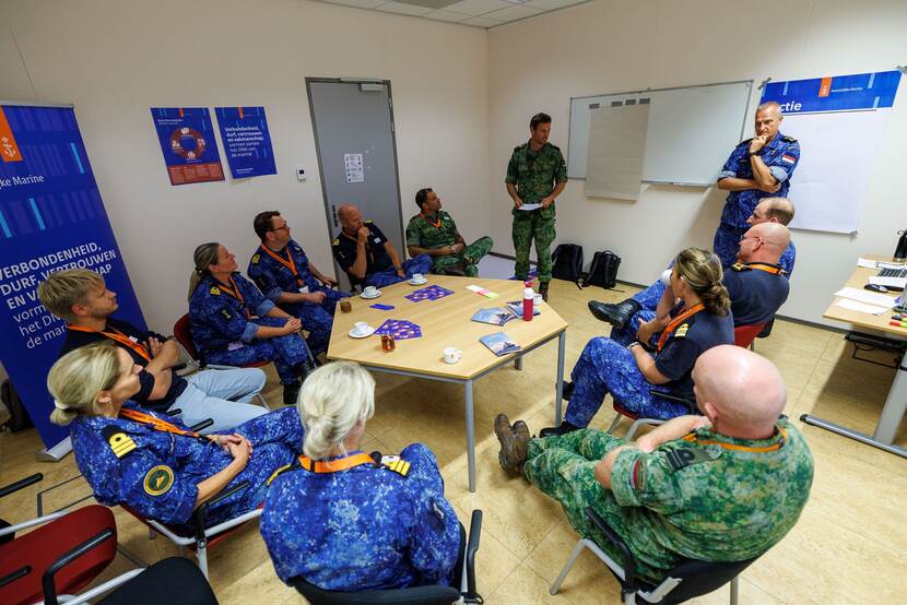 Een groep militairen zit rond een tafel tijdens een brainstorm.