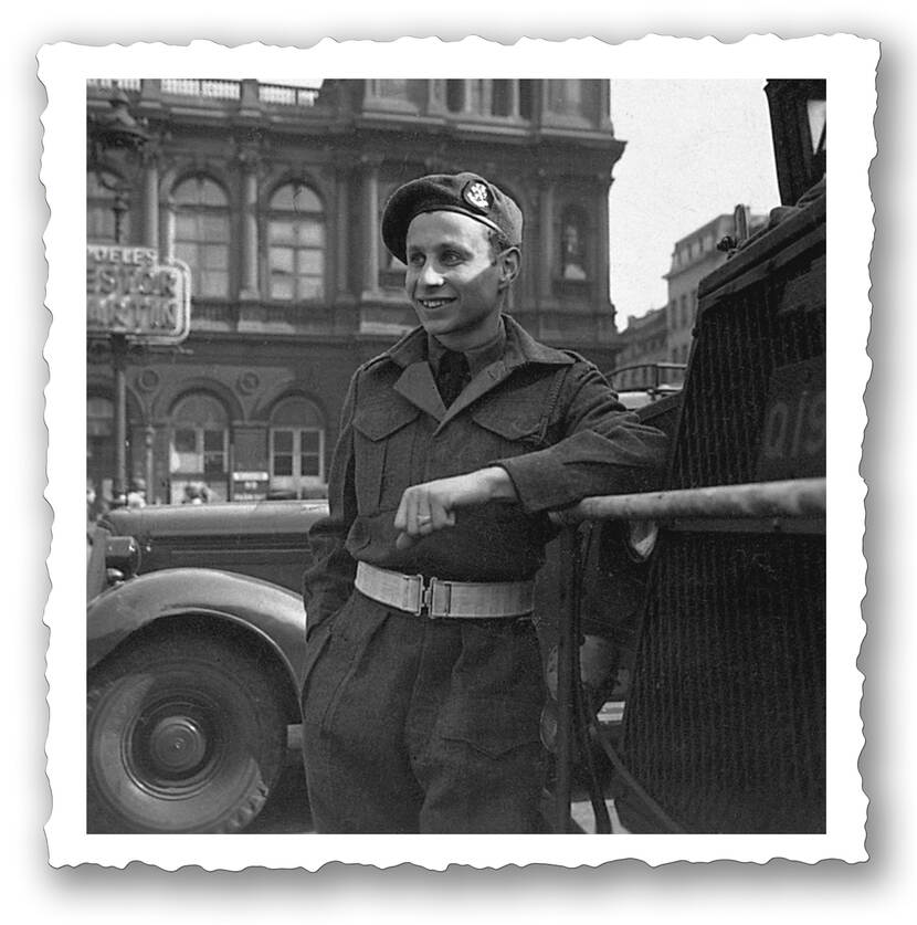 Een jongere Max Wolff leunt tegen een voertuig aan, tijdens de bevrijding van de Belgische hoofdstad Brussel. Hij glimlacht.