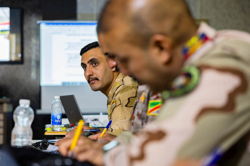 Een Irakese militair met een grote snor kijkt naar de NAVO-docent.