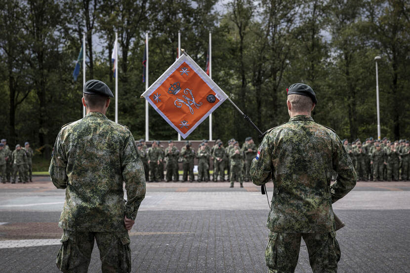 2 militairen met een oranje vlag in het midden.