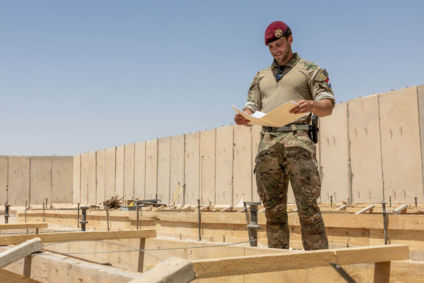 Luitenant Stefan kijkt naar een plattegrond, temidden van een bouwplaats in Irak
