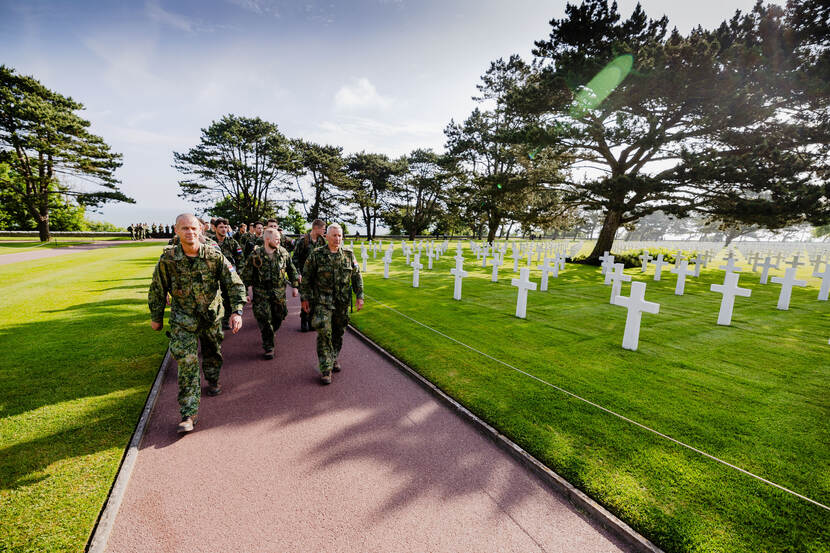 Een groepje militairen van 17 Painfbat GFPI loopt langs de rijen met witte kruizen op de Amerikaanse begraafplaats in Colleville-sur-Mer.