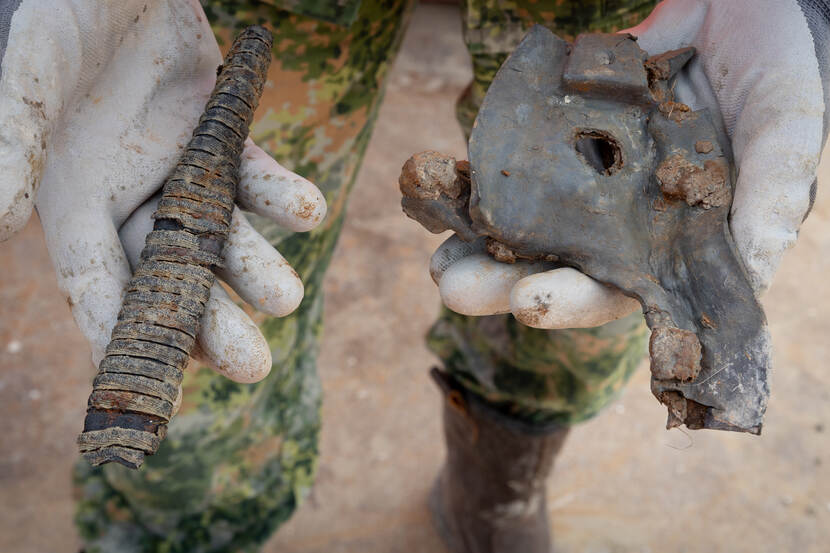 Twee resten van uitrustingsstukken in de hand van militair sergeant-majoor Kai van Emmen, van dichtbij gefotografeerd in de handen, gehuld in rubberen handschoenen.