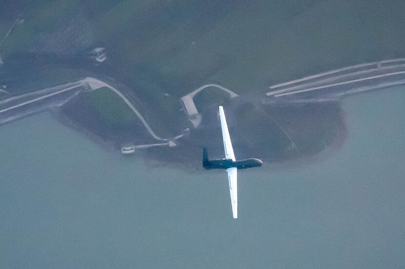 Hoog in de lucht vliegt een RQ-4D over het landschap.