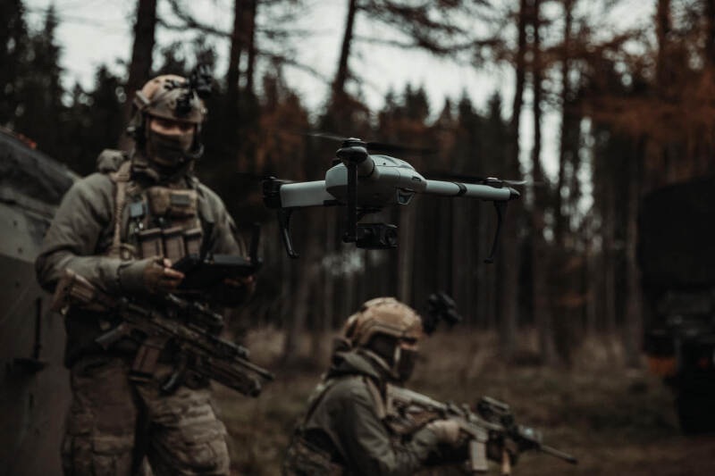 Een militair kijkt naar een opstijgende drone, die op de voorgrond voor de camera zweeft.