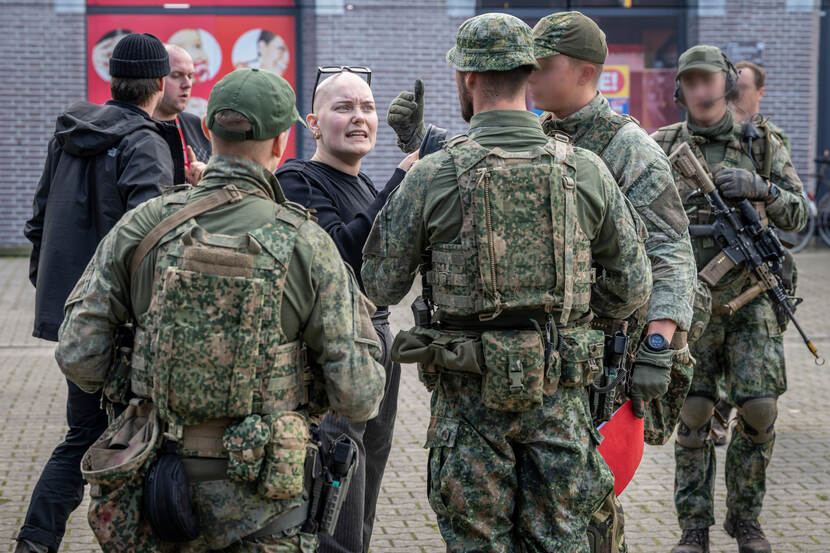 Een dame staat fulminerend tegenover enkele militairen.