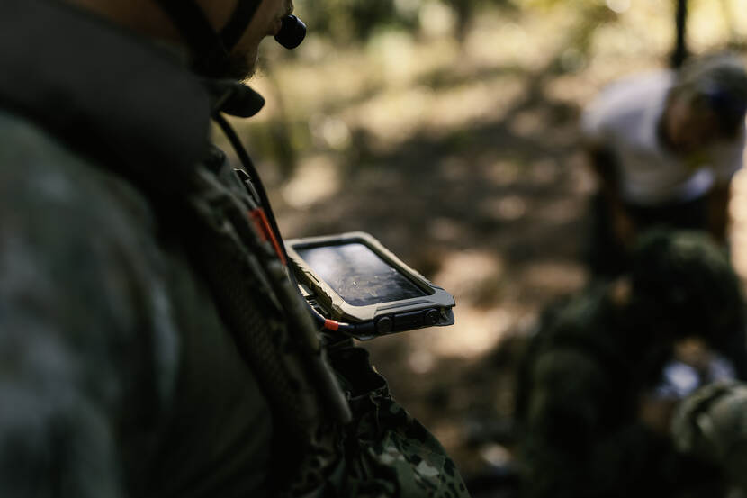 Een scherm hangt aan het OPS-vest van de militair. Het scherm is niet zichtbaar.