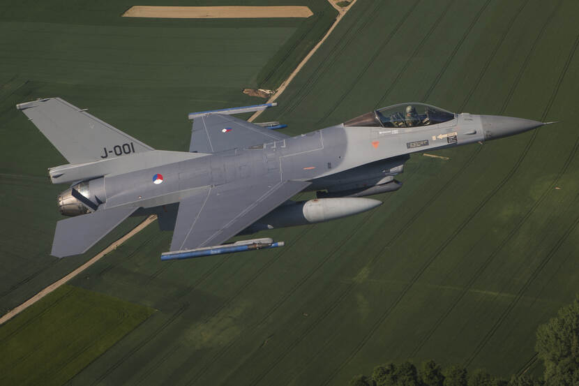 F-16 vliegt over weilanden.