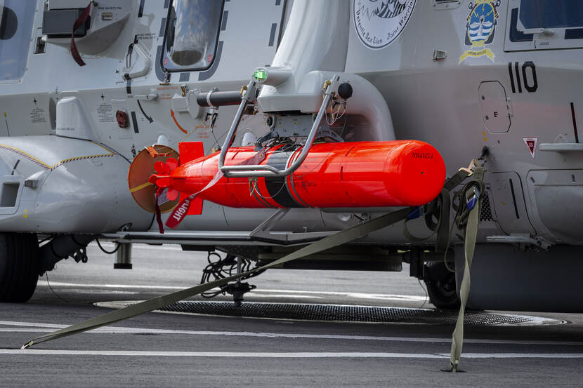 Close-up van een oranje dummy torpedo onder een stilstaande NH90.
