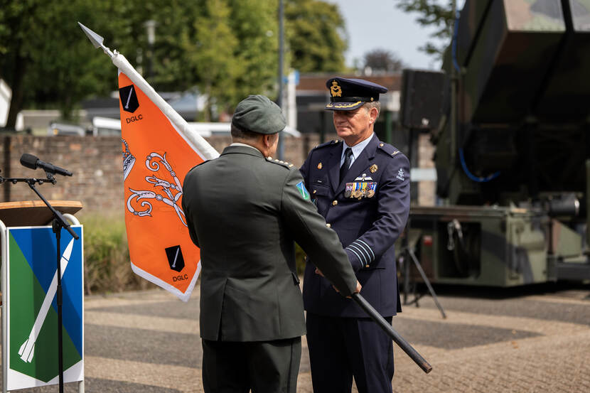 Overdracht van een vlag door een landmacht en een luchtmachtmilitair.