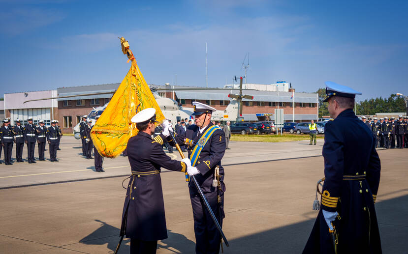 Overdracht van een vlag door twee marinemilitairen.