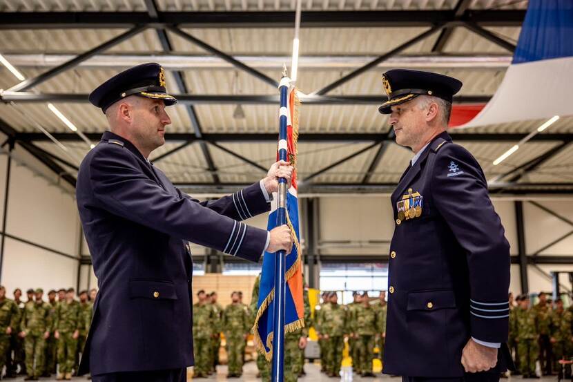 Overdracht van een vlag door twee luchtmachtmilitairen.