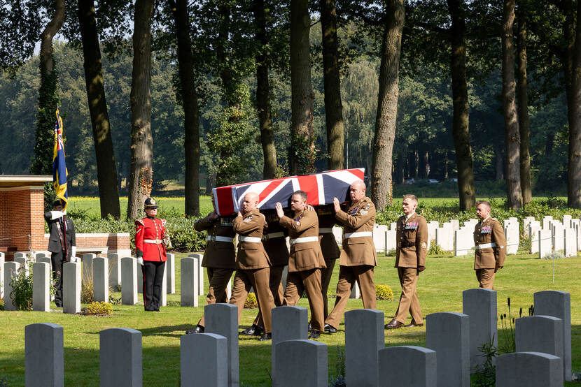 Militairen dragen een lijkkist met daarop een Britse vlag.