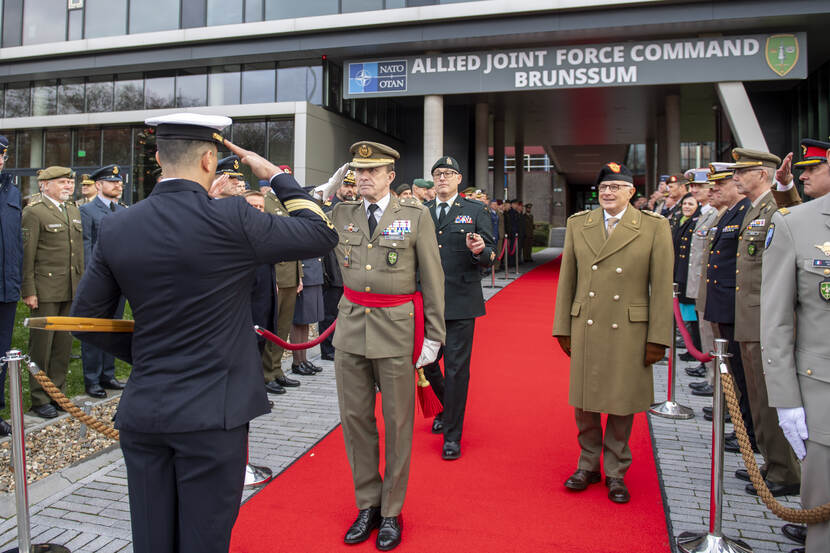 Militaire groet tussen de generaals voor het gebouw van het Joint Force Command in Brunssum. Langs de zijlaan staan militairen.