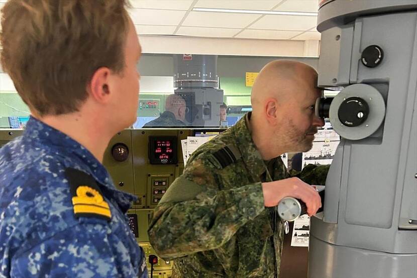 Generaal-majoor Robert Adang tuurt door een kijker op een marineschip.